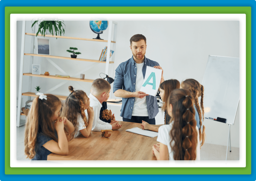 Teacher shows letter "A" to young students at table.