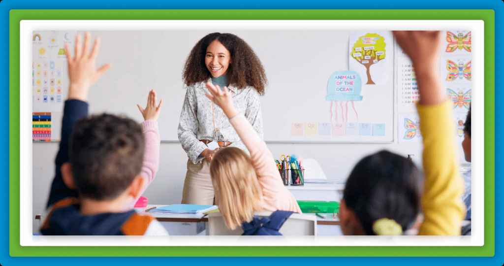 Smiling teacher gestures to students with raised hands.