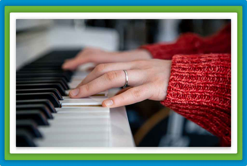 Hands playing a white and black piano keyboard.