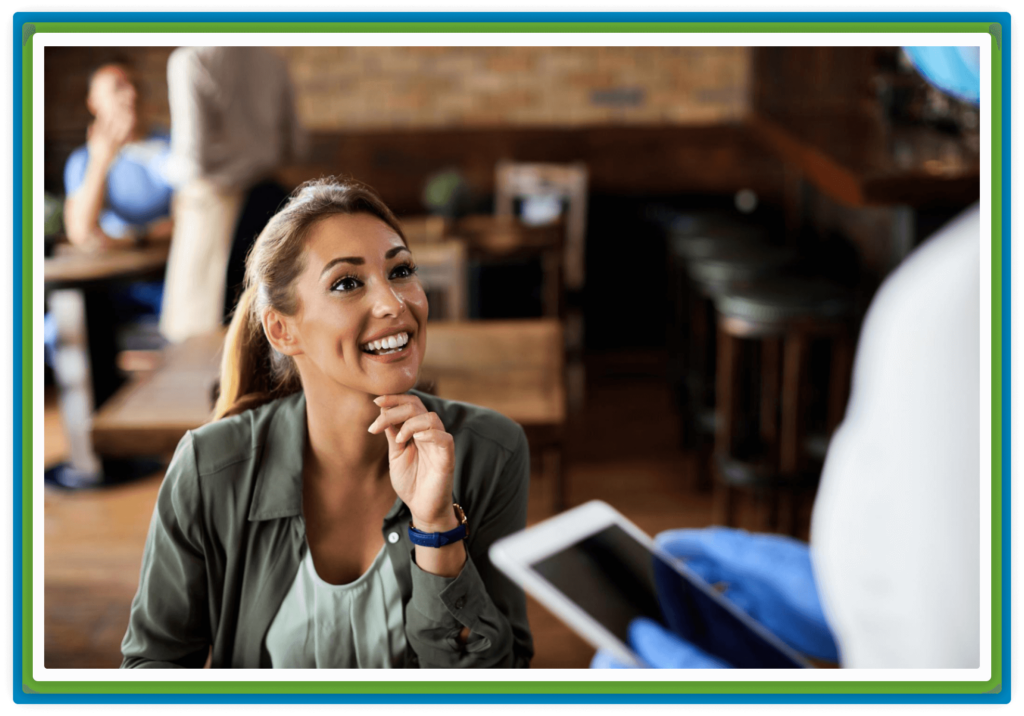 Smiling woman in cafe looks at server with tablet.