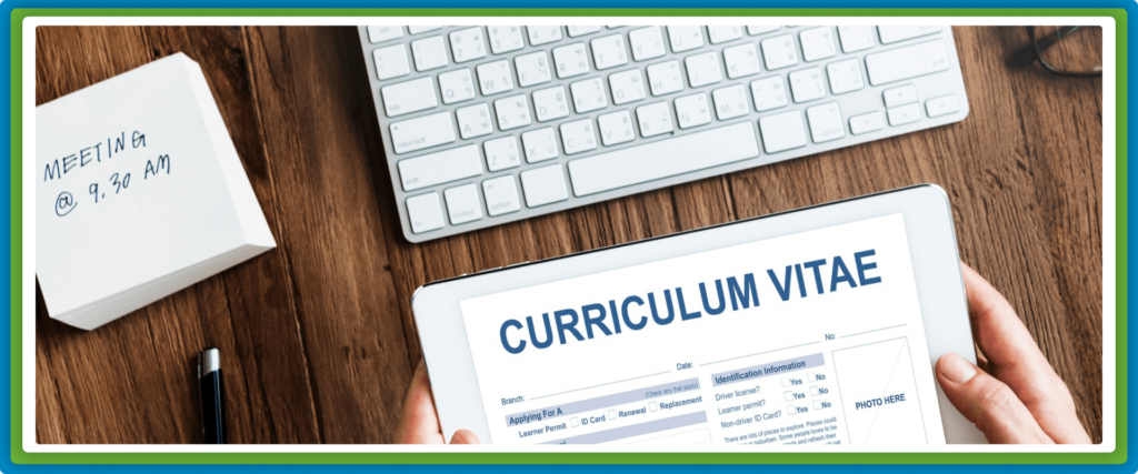 Hands hold a tablet displaying "CURRICULUM VITAE" on a wooden desk.