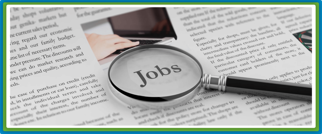 A magnifying glass highlights the word "Jobs" on a newspaper.